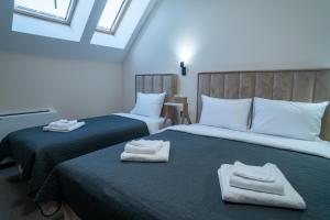 two beds in a room with towels on them at SEE YOU Apartments in Niš
