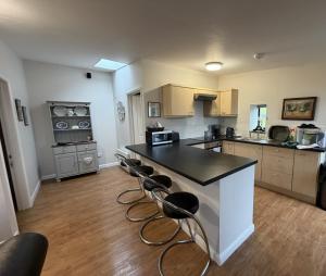 a large kitchen with a counter and chairs in it at The Old Stable, Llancarfan in Llancarvan