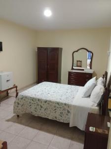 a bedroom with a bed with a dresser and a mirror at Residencial Monte Sintinha in Espargos +2 photos