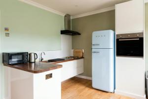a kitchen with white cabinets and a refrigerator at Stylish Morpeth Cottage with Log Burner, Garden and Free Parking in Morpeth
