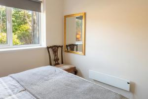 a bedroom with a bed and a mirror and a chair at Stylish Morpeth Cottage with Log Burner, Garden and Free Parking in Morpeth +10 photos