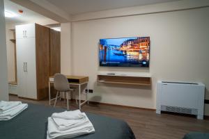 a room with a tv on a wall with a bed at SEE YOU Apartments in Niš