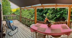 a wooden deck with a table and chairs on it at Chalet paisible dans les Cévennes avec sauna privé in Dourbies