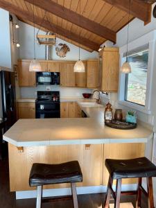a kitchen with wooden cabinets and a island with two stools at The Riptide Retreat in Shelton +24 photos