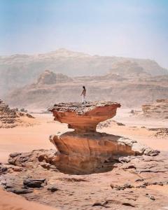 a person standing on a rock in the desert at Bedouin Life Camp in Aqaba