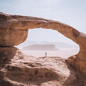 a person walking through an arch in the desert at Bedouin Life Camp in Aqaba