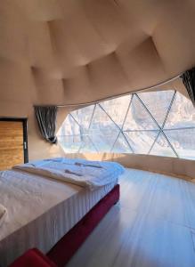 a bedroom with a bed in front of a large window at Bedouin Life Camp in Aqaba