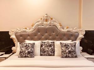 a bed with a gold and white headboard and pillows at Most Awarded Property In Mussoorie in Mussoorie