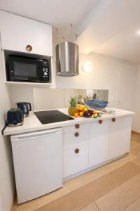 a white kitchen with a counter with fruit on it at Acmé Appartement 200 m du lac d'Annecy in Angon