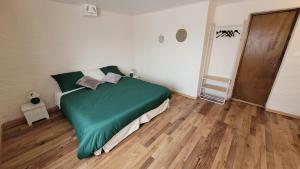 a green bed in a room with a wooden floor at Gîte familial avec jardin privatif - près de Rocamadour et Padirac in Saint-Michel-de-Bannières