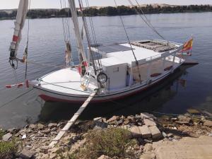 a boat is docked in the water on the shore at Royal Felucca - Shared Amazing Sailing in Aswan