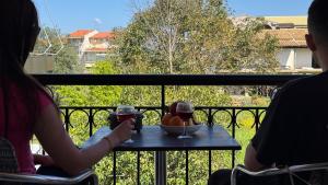 two people sitting at a table with glasses of wine at Marili Apartments in Roda