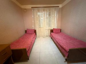 two beds in a small room with pink sheets at Hotel MANTASHOV in Meghri
