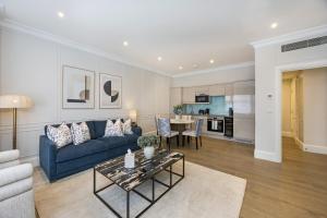a living room with a blue couch and a table at Buckingham & Lloyds Knightsbridge in London