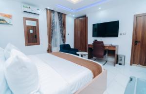 a hotel room with a bed and a desk and a television at VHS Vinchee Suites II in Lagos
