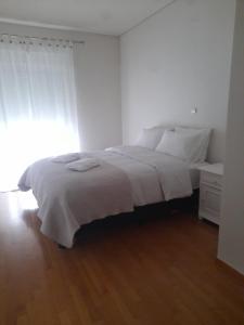 a white bedroom with a bed and a window at Kings and Queens 1 in Larisa
