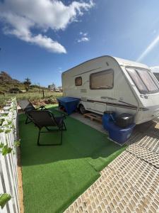 a white rv parked on a lawn with a table and chairs at Little hideaway in Costa da Caparica