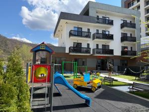a playground in front of a building with a slide at Pensiunea LOFT Căciulata in Caciulata