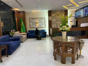 a lobby with blue couches and a table with flowers at فندق اسفار الحجاز 2 in Al Masfalah