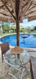 a table and chairs under an umbrella next to a swimming pool at 4 Ventos House in São Miguel do Gostoso
