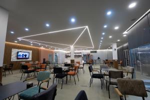 a restaurant with tables and chairs and a flat screen tv at Bar Hotel Orgito in Lushnjë
