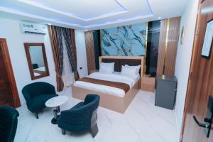 a bedroom with a bed and two chairs and a television at VHS Vinchee Suites II in Lagos