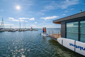 two people are standing on a paddle board on a dock at Floatinghouse Seestern in Klitten