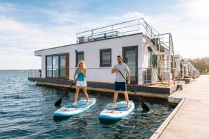 a man and a woman on paddle boards in the water at Floatinghouse Neptun - LP3 in Vetschau +14 photos