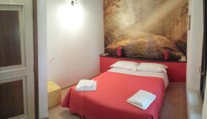 a bedroom with a red bed with two towels on it at Agriturismo Casal Taccone in Tarquinia