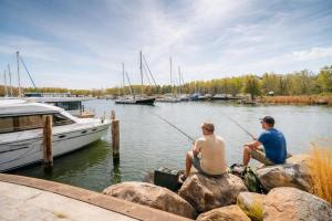 two men sitting on rocks fishing at a marina at Floatinghouse Marama - LP10 in Peenemünde