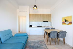a living room with a blue couch and a table at Perla Luxury Apartment - Private Patio & Parking in Vlorë