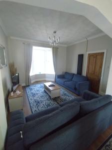 a living room with a blue couch and a table at large 4 bedroom in Pembroke Dock