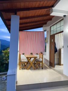 a patio with a table and chairs and a red and white wall at Guest House Brahimasi in Çorovodë