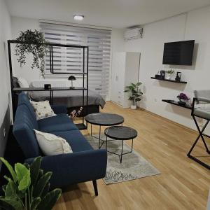 a living room with a blue couch and two tables at Sarajevo s Secret -Airport Apartment East Sarajevo in Donje Mladice