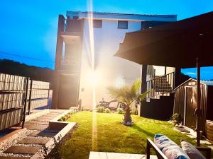 a house with the sun shining on a yard at Lemba, apartman 4 zvjezdice in Opuzen