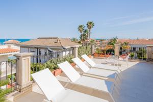 a row of white lounge chairs on a patio at Villa Raphael in Avola