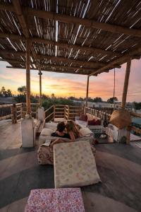 a man and a woman laying on a bed on a patio at Paracas Desert Lodge&Tours in Paracas
