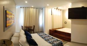 a bedroom with a bed and a tub and a television at Hotel Ucla Center in Valledupar