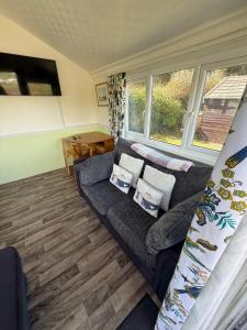 a living room with a couch and two windows at Chalet 5 Clarach Bay in Aberystwyth
