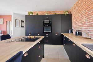 a kitchen with black cabinets and a brick wall at Maison de charme, Gorges Ardèche et Nature in Vagnas +24 photos