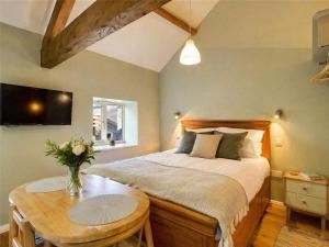 a bedroom with a bed with a table and a tv at Wagtail Lodge in Foy