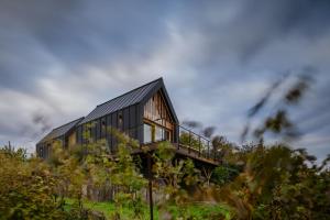 a black house on top of a hill with trees at Kabiny Kravák in Znojmo