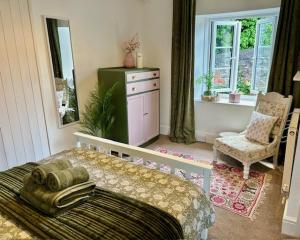 a bedroom with a bed and a chair and a mirror at Mews Cottage in Torquay