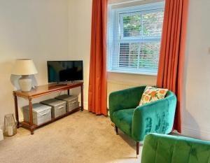 a living room with a green chair and a television at Mews Cottage in Torquay