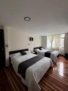 three beds in a room with wood floors at Hotel San Alejo in Ipiales