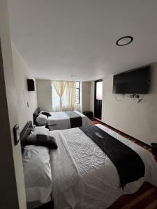 a bedroom with two beds and a flat screen tv at Hotel San Alejo in Ipiales +6 photos