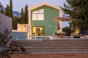 a house with a pool and a table and an umbrella at Black Mountain Villas in Kefallonia