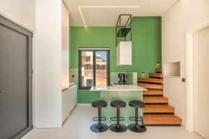 a kitchen with green walls and stools at Black Mountain Villas in Kefallonia