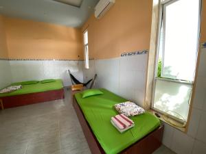 a room with two green beds and a window at Kim An Sadec Garden House in Ấp Tân An (2)