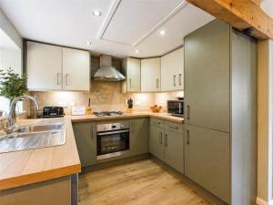 a kitchen with stainless steel appliances and wooden floors at Wagtail Lodge in Foy